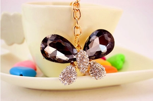 Détail d'un porte-clés papillon avec cristaux gris en poire et strass blancs scintillants