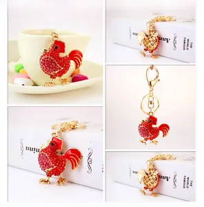 Dettaglio portachiavi a forma di gallo dorato con strass rossi e chiusura a moschettone