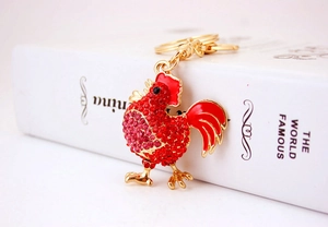 Dettaglio portachiavi a forma di gallo rosso con strass e chiusura a moschettone dorata