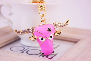 Close-up of pink enamel bull head keychain with sparkling rhinestones and gold-tone metal frame