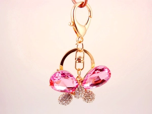 Détail d'un porte-clés papillon en cristal rose avec strass brillants et fermoir doré