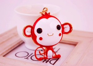 Close-up of cute cartoon monkey keychain with red and white enamel and rhinestone eyes