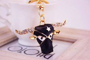 Detailed close-up of a gold-plated bull keychain with black enamel and sparkling rhinestones