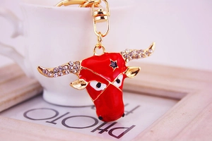 Close-up of red enamel bull head keychain with gold plating and white rhinestones