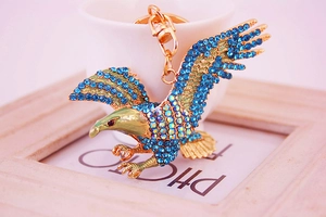 Macro detail of gold eagle keychain featuring sparkling blue rhinestones and enamel finish