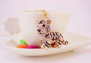 Detailansicht eines funkelnden Tiger-Schlüsselanhängers an einer weißen Kaffeetasse