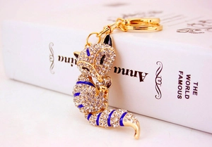 Detail shot of a crystal fox keychain with gold metal base and blue enamel stripes
