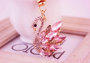 Macro shot of gold swan keychain with pink crystals and sparkling white rhinestones