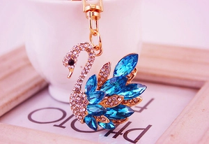 Detail of swan keychain with blue crystal wings and gold-plated clasp on props