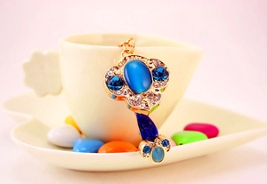 Dettaglio di un portachiavi cinese vintage dorato con strass blu e pietra occhio di gatto