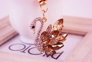 Detailed macro view of gold-tone swan keychain with champagne crystals and white rhinestones