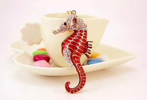 Détail du pendentif hippocampe en émail rouge avec strass brillants sur base dorée