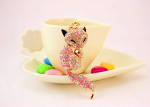 Detail of crystal fox keychain with pink enamel stripes hanging on a cup edge