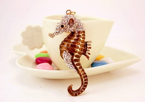 Vue macro d'un pendentif hippocampe doré avec cristaux et émail marron brillant