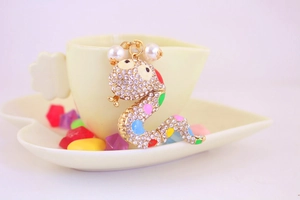 Close-up of a golden snake keychain with colorful rhinestones and pearl details