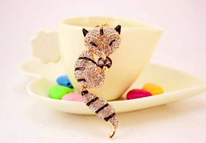 Detail of fox-shaped brooch with crystals and black enamel hanging on a cup rim