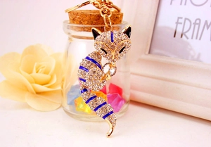 Close-up of crystal fox keychain with blue enamel stripes and gold metal clasp