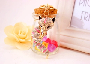Detail of crystal fox keychain with pink enamel stripes on a gold base and white rhinestones