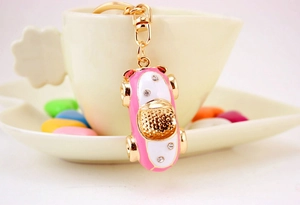 Close-up of pink and white car keychain with crystal accents on a coffee cup