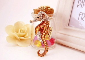 Détail d'un porte-clés hippocampe en émail orange et strass brillants sur métal doré