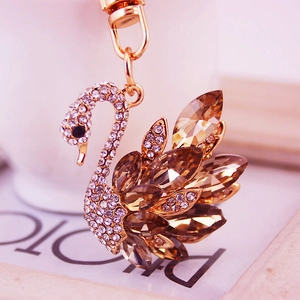 Golden swan keychain with amber crystals and white rhinestones on a decorative background