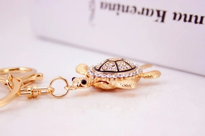 Vue latérale d'un porte-clés tortue dorée orné de strass blancs scintillants
