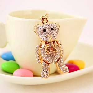 Sparkling crystal teddy bear keychain with gold finish on a white ceramic cup