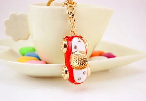 Detail of a red car keychain with white crystals hanging on a white coffee cup