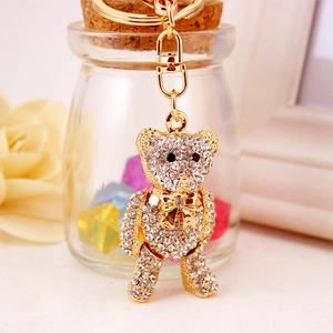 Sparkly bear keychain with white rhinestones and golden bowknot on warm aesthetic background