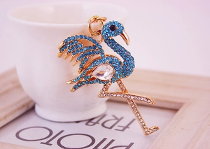 Vue rapprochée d'un porte-clés flamant rose doré orné de strass bleus et blancs brillants