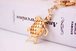Gros plan d'un porte-clés tortue dorée avec des motifs de cœurs évidés sur la carapace