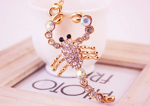 Detailed view of scorpion keychain with sparkling rhinestones on a white ceramic cup