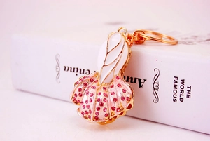 Detail of creative gold metal cabbage keychain with white enamel and pink rhinestones