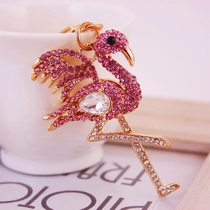Porte-clés flamant rose brillant avec anneau doré posé sur une tasse décorative blanche