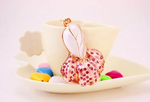 Detailed close-up of a cabbage-shaped pendant with pink rhinestones and white enamel finish