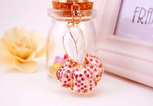 Detail of creative fish tail keychain with pink rhinestones and white enamel finish