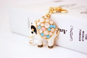Close-up of white elephant keychain with opal stones and golden metal outlines