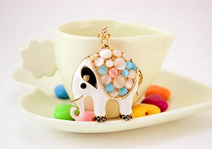 Close-up of golden elephant keychain with colorful opal stones and enamel on coffee cup
