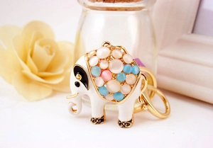 Close-up of a golden elephant keychain with white enamel and colorful opal stones