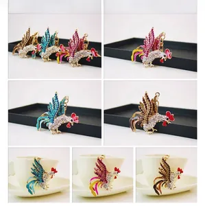 Détail du porte-clés coq en cristal avec strass multicolores sur le bord d'une tasse