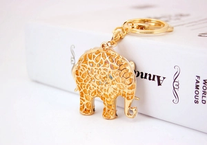 Close-up of golden elephant keychain with hollow pattern and opal crystal inlay