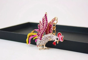 Gros plan du porte-clés coq avec strass roses et fermoir mousqueton en alliage doré