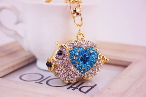 Détail macro du porte-clés cochon avec strass blancs et motif de cœur bleu brillant