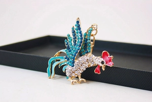 Détail d'un porte-clés coq en cristal étincelant avec strass bleus et fermoir mousqueton doré