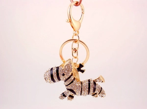 Macro detail of zebra keychain with gold plating, white rhinestones and black enamel strips