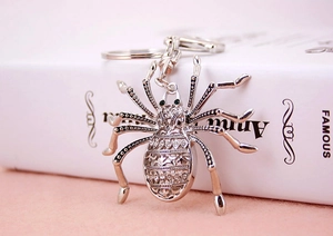 Detail showing crystal spider keychain with silver plating and green gem eyes
