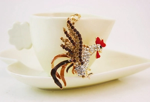 Détail d'un porte-clés coq étincelant avec des strass colorés sur une tasse blanche