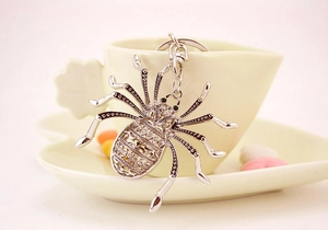Close-up of a silver spider keychain with rhinestones hanging on a coffee cup