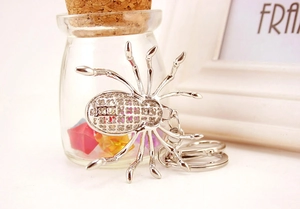 Detailed close-up of a silver spider keychain with intricate cutout patterns on its back