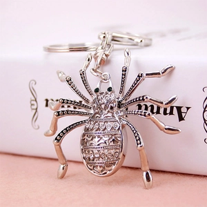 Sparkling spider keychain with silver metal hollow texture and green gemstone eyes